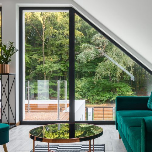 Panorama of stylish, attic living room with emerald color furniture and brick wall