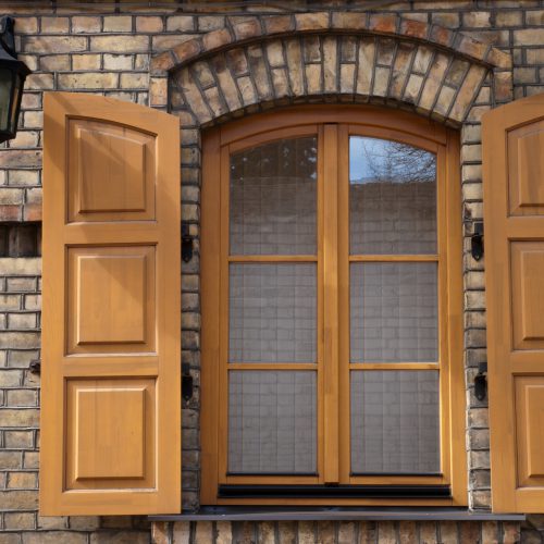 window in a brick wall with wooden shutters