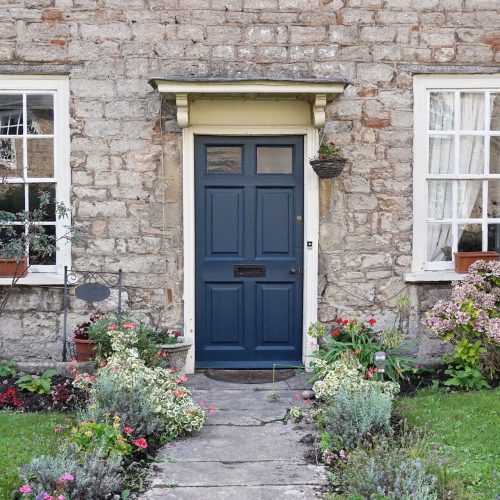 front door of old house with flowers in a garden