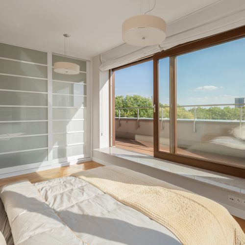 Elegant bedroom with big bed and window wall open to balcony